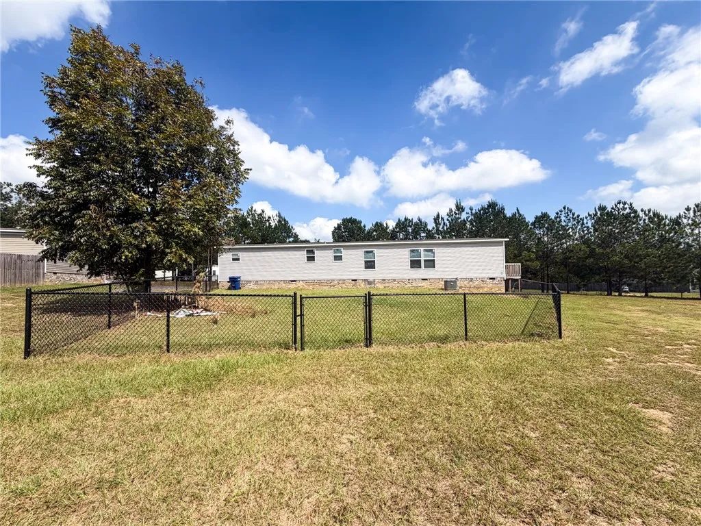 A spacious grassy lawn features a fenced enclosure set against a classic single-story home.