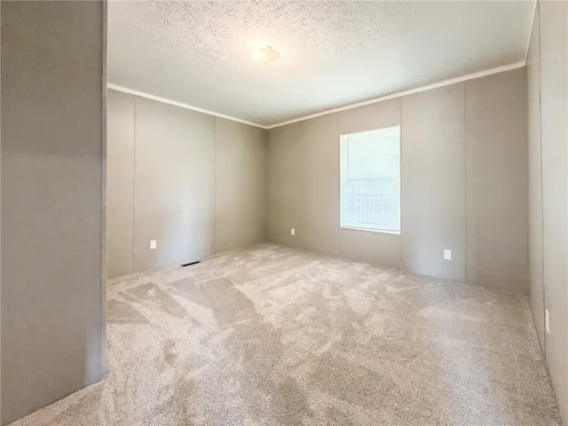 Plush wall-to-wall carpeting and a bright window define this versatile bedroom space.