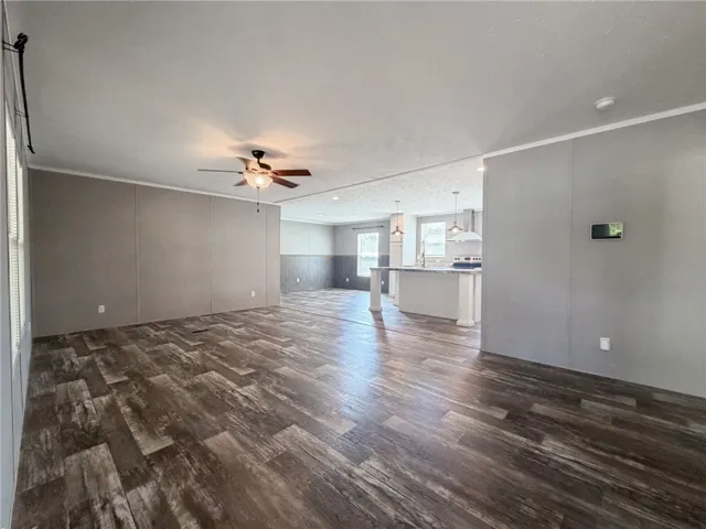 Rich wood-look flooring anchors this open living space flowing seamlessly toward the kitchen.