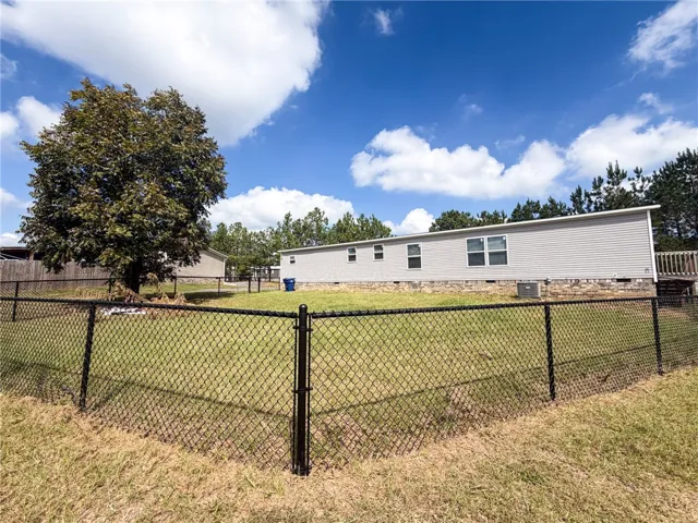 A spacious, chain-link fenced yard surrounds the rear exterior of this siding-clad home.