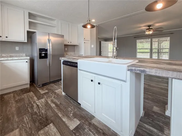 Rich wood-look flooring anchors a modern culinary space boasting a central island with farmhouse sink.