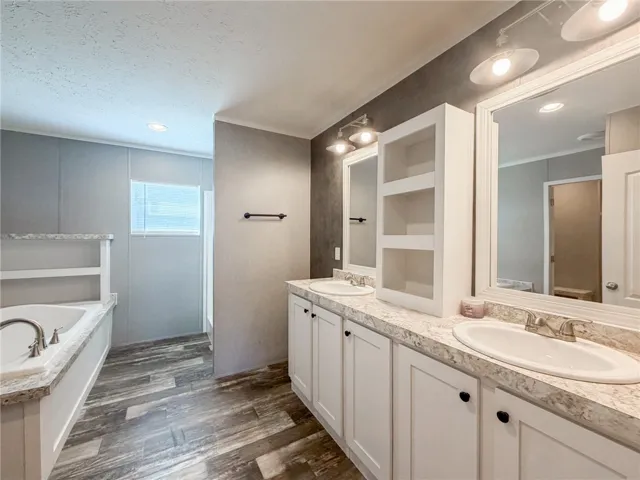 Wood-look flooring complements the spacious dual vanity and soaking tub in this refined bathroom layout.