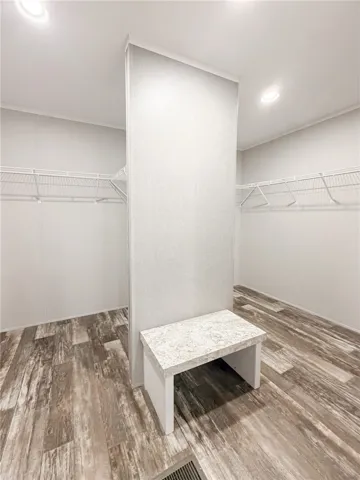An integrated bench seat and wire shelving maximize storage within this well-lit walk-in closet.