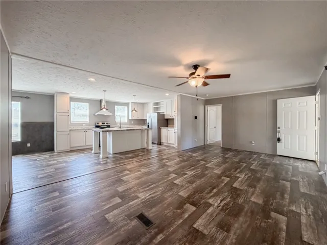 An open layout connects the spacious living area to the kitchen featuring wood-look flooring.