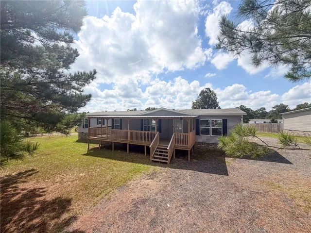 A spacious wooden front porch welcomes guests to this classic one-level vinyl-sided home.