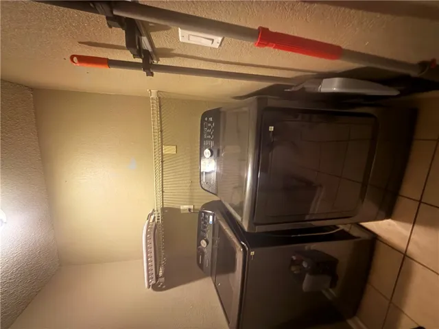 Practical utility space features tiled flooring and built-in wire shelving above the laundry appliances.