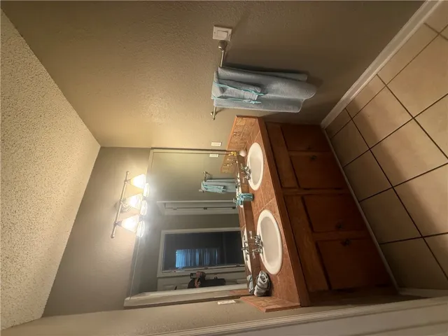 Tiled flooring and dual sinks on a wooden vanity define this functional bathroom space.