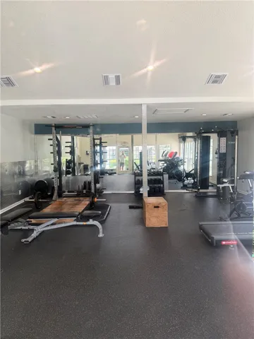 A fully equipped home fitness center features specialized rubber flooring and recessed lighting.