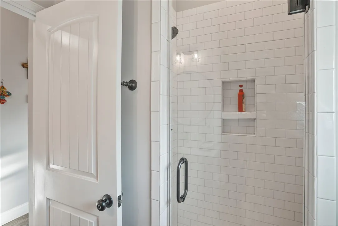 Crisp subway tile lines this modern walk-in shower featuring a glass door.