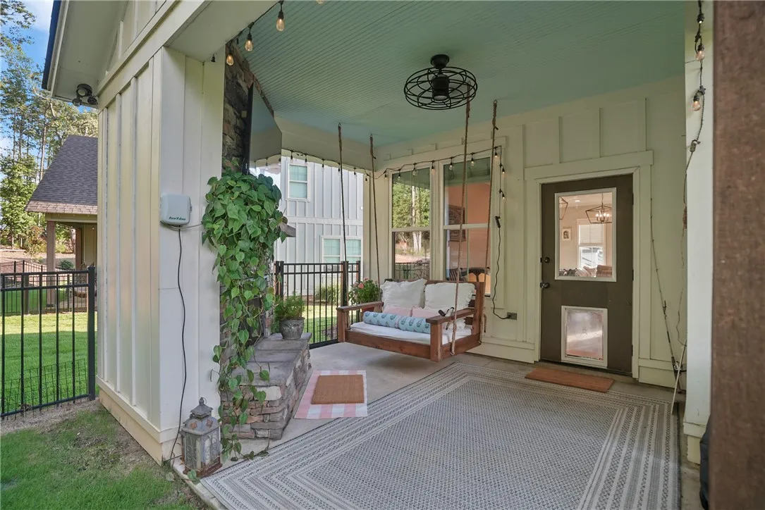 A spacious covered back porch features board and batten siding alongside a stone fireplace.