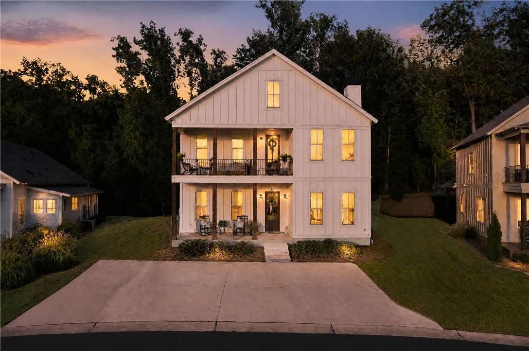 A classic board and batten facade stands illuminated against a backdrop of mature trees.