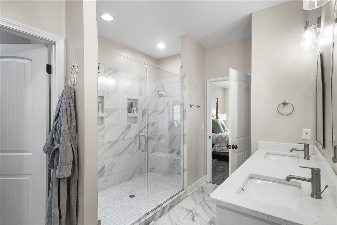 Polished tile flooring and a dual-sink vanity anchor this bright primary bathroom.