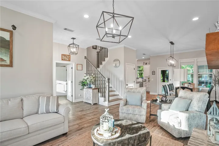 Hardwood floors and high ceilings frame an open, airy living space with transitional staircase details.