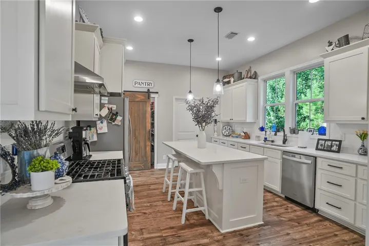 Rich wood flooring anchors this culinary space beneath recessed lighting and a central island.