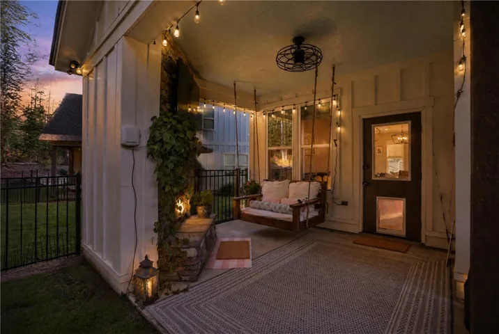 An inviting covered porch features board and batten siding alongside a stone fireplace.