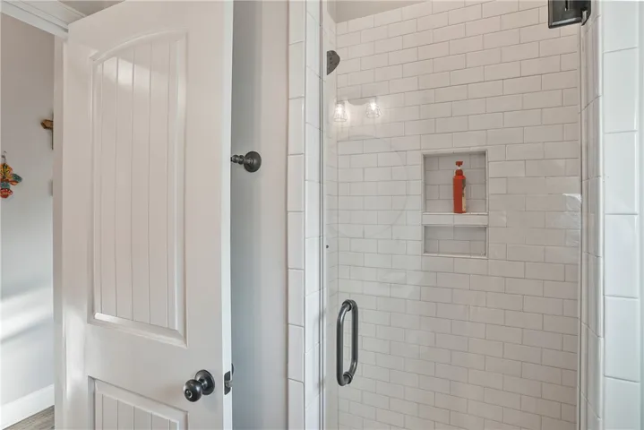 Crisp subway tile lines this modern walk-in shower featuring a glass door.