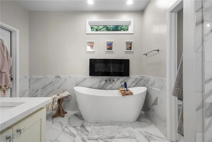 Elegant marble-style tiling surrounds a freestanding soaking tub in this light-filled modern bathroom.