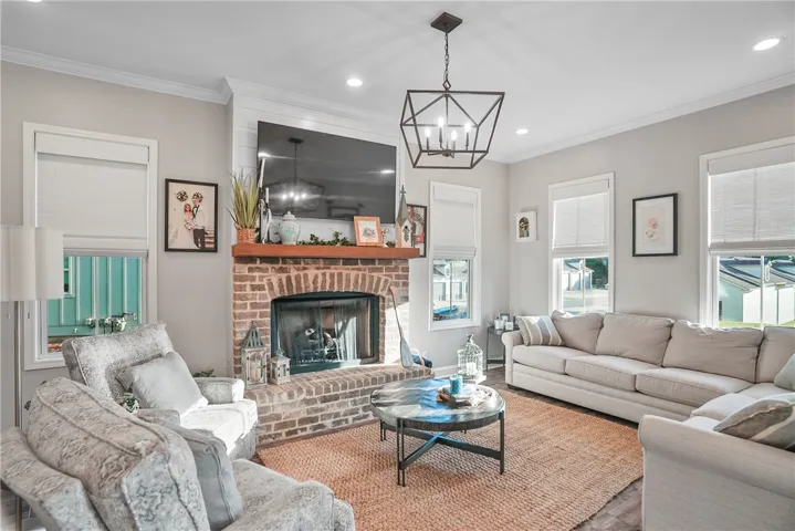 An inviting brick fireplace acts as the centerpiece of this spacious, window-lined living room.