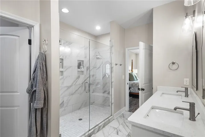 Polished tile flooring and a dual-sink vanity anchor this bright primary bathroom.