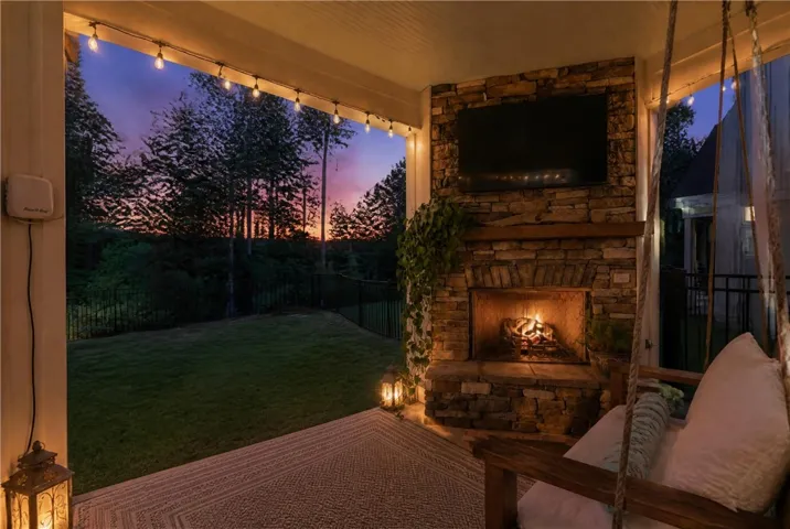 A stone fireplace anchors this covered back porch overlooking a private fenced yard.