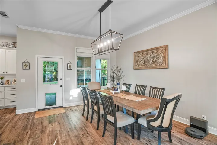 Rich wood flooring and subtle crown molding define this welcoming, light-filled dining space.