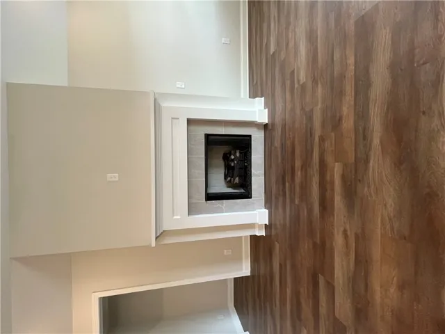 Rich wood-inspired flooring complements a classic tile-trimmed fireplace under soaring high ceilings.