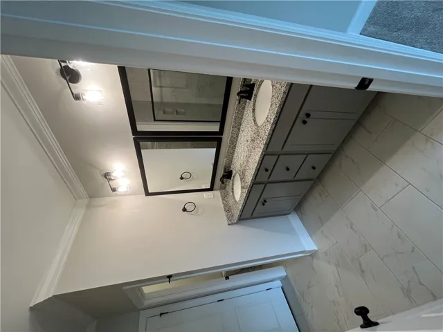 Elegant tile flooring complements a modern double vanity featuring polished granite counters.
