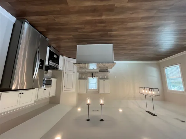 Gleaming wood floors anchor an open kitchen featuring a central island and stainless steel appliances.