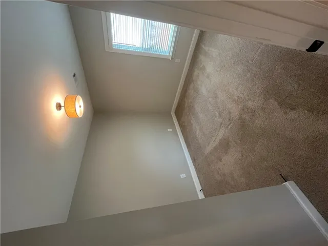 A quiet bedroom offers soft carpeting and a bright window looking out to the property.