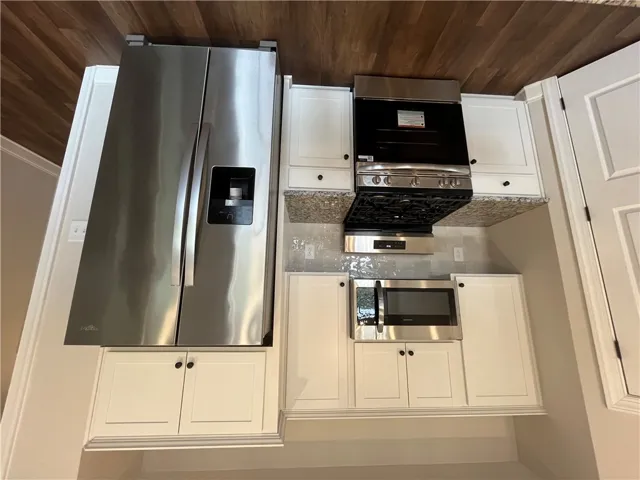 Gleaming stainless steel appliances complement the clean cabinetry and rich wood-style flooring.