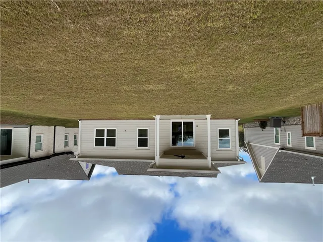An expansive green lawn stretches behind this modern home featuring a covered back porch.