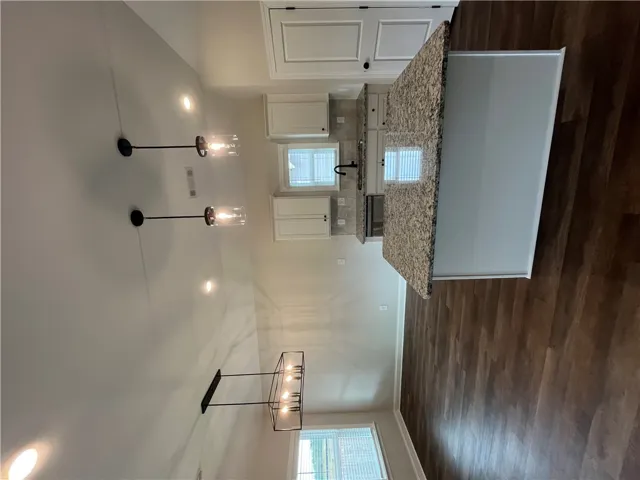 Rich wood-look flooring complements the stone counters and open layout of this modern kitchen.