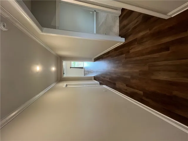 Polished wood floors and elegant crown molding define this welcoming hallway transition.