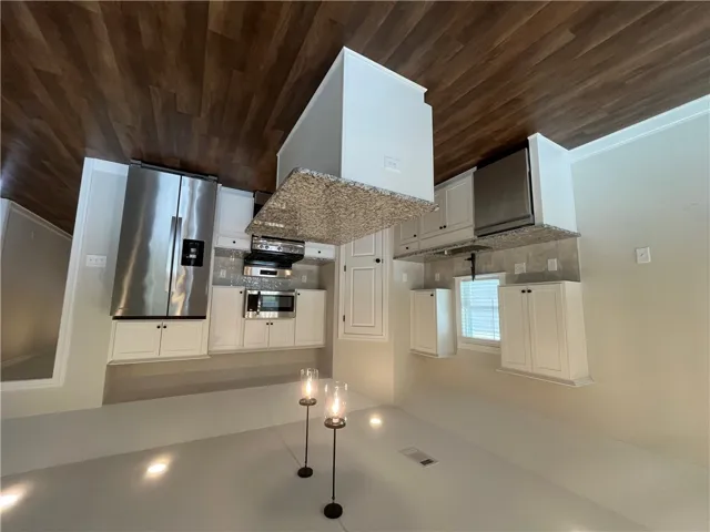 Rich wood flooring contrasts beautifully with classic white cabinetry and durable granite countertops.