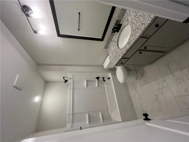 Polished tile flooring and granite countertops anchor this updated, functional bathroom.
