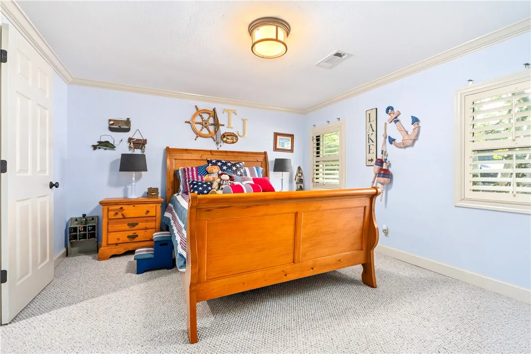 Plentiful natural light fills this cozy bedroom featuring soft textured carpeting and classic crown molding.