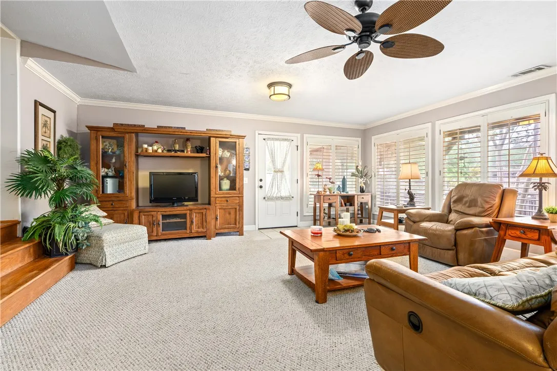 Natural light streams through plantation shutters into a spacious living area featuring built-in cabinetry.