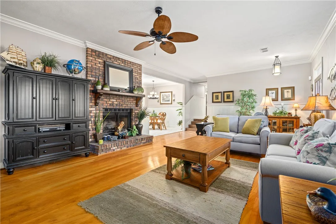 Gleaming hardwood floors run through a comfortable living area anchored by a brick fireplace.