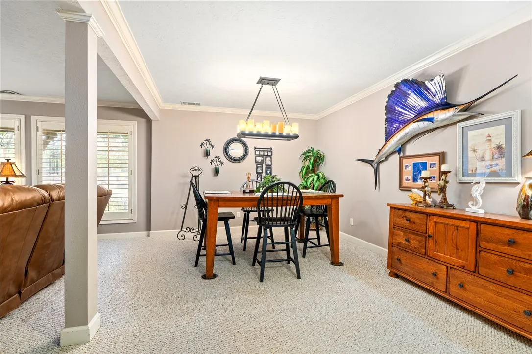 Crown molding and textured carpet frame this comfortable dining space opening to the living area.