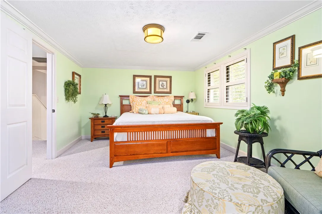 Plentiful natural light fills this bedroom featuring crown molding and classic plantation shutters.