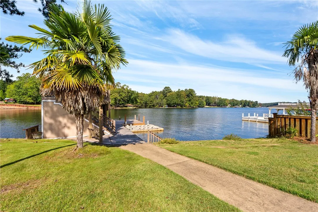 A concrete pathway leads past green lawns and swaying palms to the private boat dock.