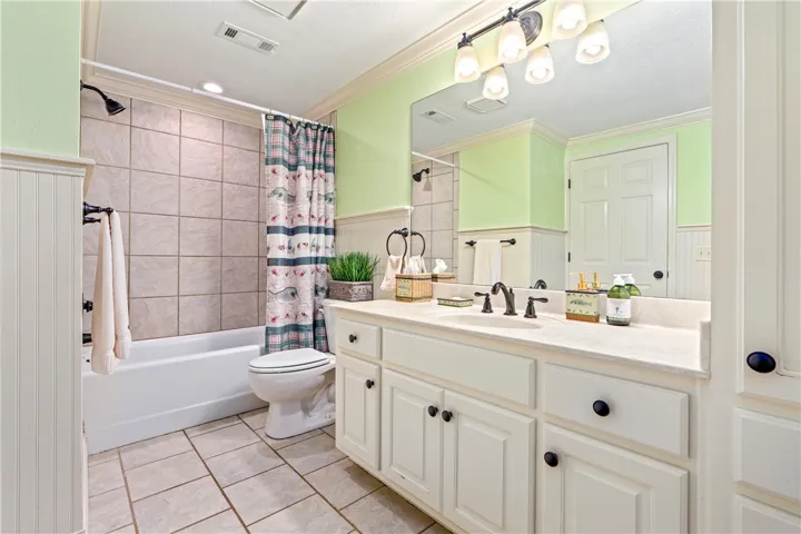 Beadboard wainscoting and classic floor tile frame this full bathroom featuring a spacious vanity.