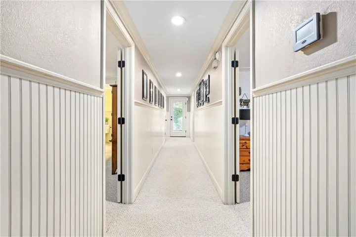 Classic beadboard wainscoting and warm carpeting line a long, welcoming hallway.