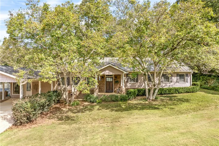 Mature trees shade a welcoming front porch set against classic shingle siding.