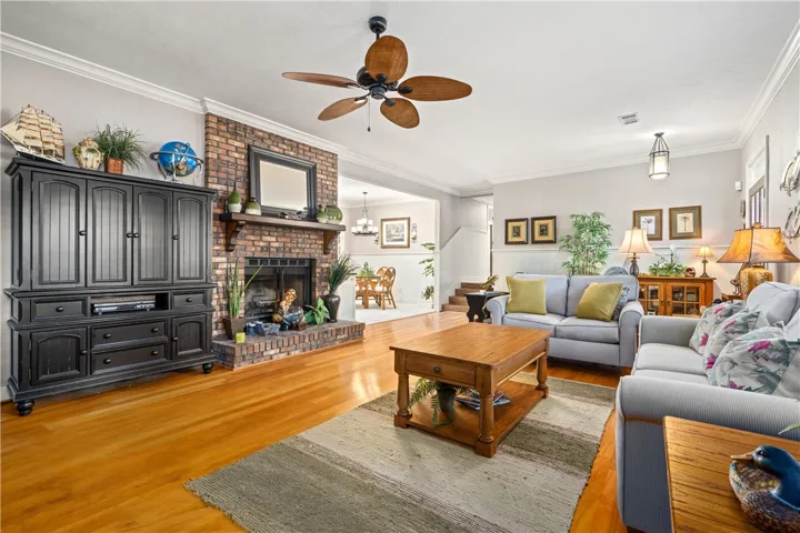 Gleaming hardwood floors run through a comfortable living area anchored by a brick fireplace.