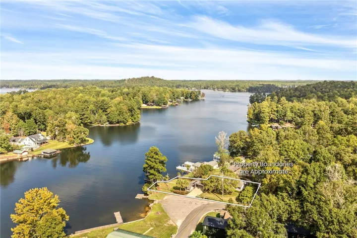 An aerial perspective showcases a lakeside property surrounded by mature trees and calm waters.