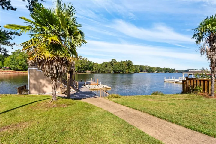 A concrete pathway leads past green lawns and swaying palms to the private boat dock.