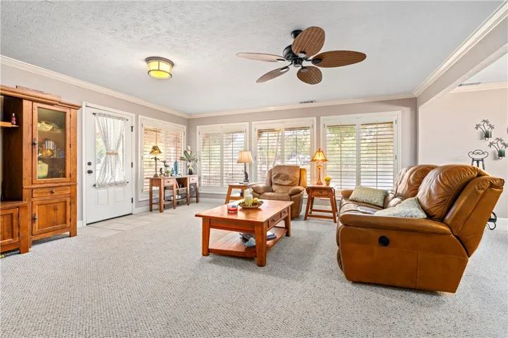 Plentiful windows with built-in shutters line this comfortable living space finished with crown molding.