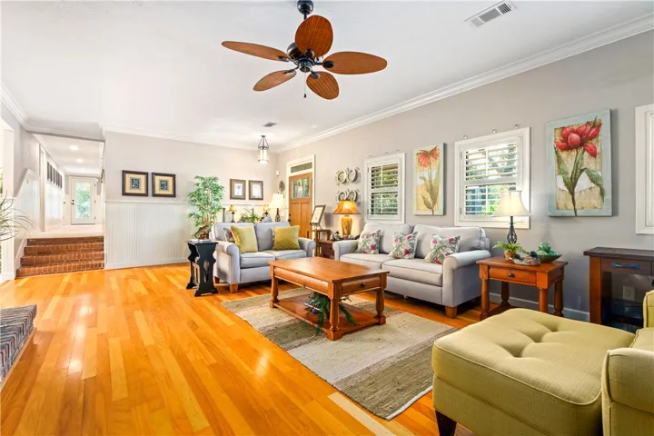 Polished hardwood floors and elegant crown molding elevate this welcoming living room.