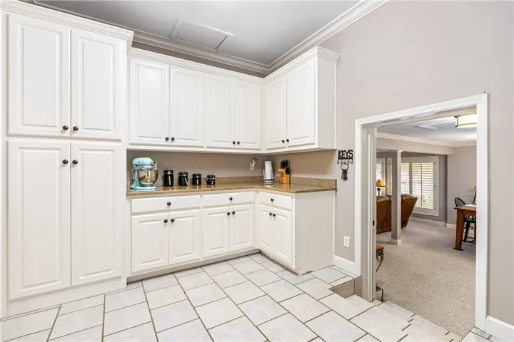 White cabinetry and granite counters complement the durable tile flooring in this bright culinary space.